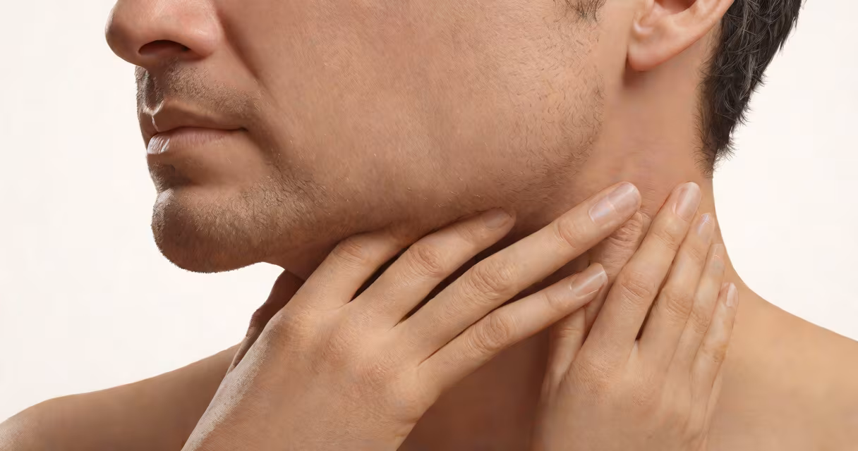 A person touching their neck to indicate throat discomfort